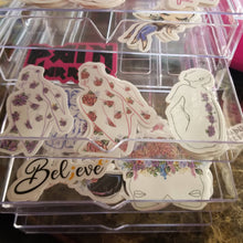 Load image into Gallery viewer, An open transparent contender full of stickers, focusing on the fibromyalgia sticker.