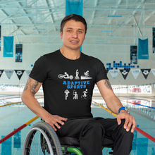 Load image into Gallery viewer, A man posting in front of an Olympic pool wearing the Adaptive Sports t-shirt with black jeans. This wheelchair is black and green.