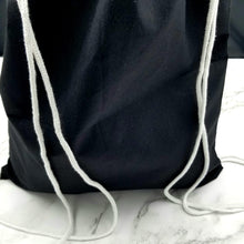 Load image into Gallery viewer, The back of the drawstring bag. The bag is black with white string handles.