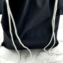 Load image into Gallery viewer, The back of the drawstring bag. The bag is black with white string handles.