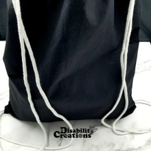 Load image into Gallery viewer, The back of the drawstring bag. The bag is black with white string handles.