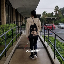 Load image into Gallery viewer, Danyelle walking up an accessible ramp using her white cane. She is wearing the Dots are my Thing #Braille Drawstring Bag.