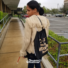 Load image into Gallery viewer, Danyelle at the bottom of an accessible ramp holding her white cane. She is wearing the Dots are my Thing #Braille Drawstring Bag
