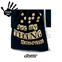 Load image into Gallery viewer, A black drawstring bag says, "Dots are my thing #Braille" in white soft foam vinyl. The word "Dots" is in Braille.