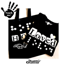 Load image into Gallery viewer, The Hope Bag underneath a folded Loved Shirt.