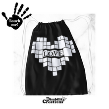 Load image into Gallery viewer,  A black drawstring bag with a white heart. In the middle of the heart, it says, &quot;Love.&quot; Surrounding &quot;Love&quot; are small and large squares forming a heart. Raised vinyl is used to feel the design and read &quot;Love.&quot;
