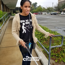 Load image into Gallery viewer, Danyelle at the bottom of an accessible ramp holding her white cane. She is wearing the Out Of My Way T-Shirt! The Disability Creations Logo is at the bottom.
