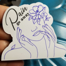 Load image into Gallery viewer, The Pain go Away sticker is resting on my fingertips.