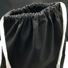 Load image into Gallery viewer, The top of the drawstring bag. The bag is black with white string handles.
