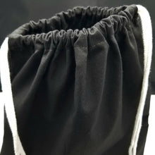 Load image into Gallery viewer, The top of the drawstring bag. The bag is black with white string handles.