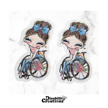 Load image into Gallery viewer, Two stickers of the &quot;A Lady Using A Wheelchair Sticker, Brown Hair.&quot; on top of a marble table.
