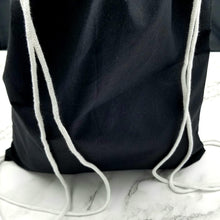 Load image into Gallery viewer, The back of the drawstring bag. The bag is black with white string handles.
