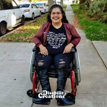 Load image into Gallery viewer, A woman using a wheelchair wearing a black T-shirt featuring a heart shape that has the word "heart" in multiple languages including American Sign Language (ASL).
