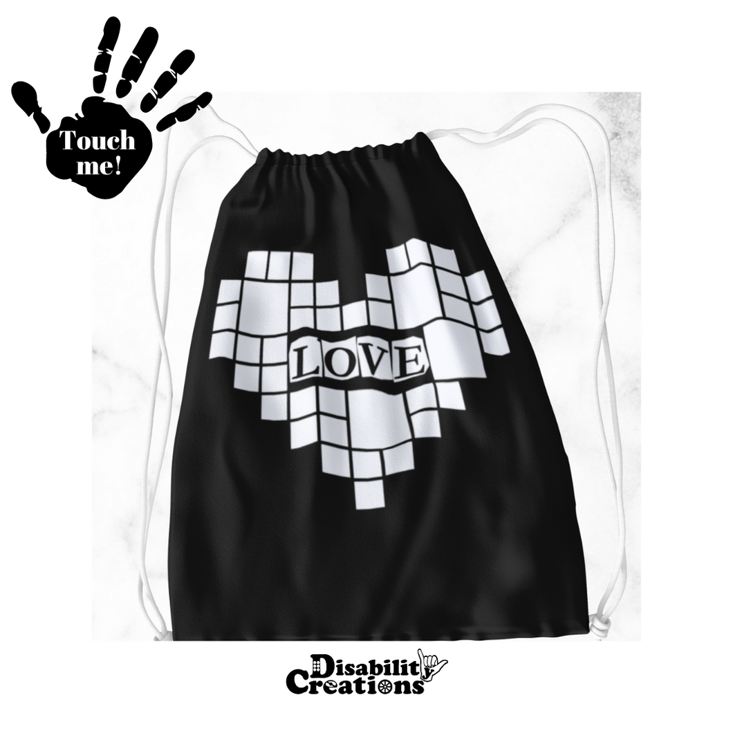  A black drawstring bag with a white heart. In the middle of the heart, it says, 