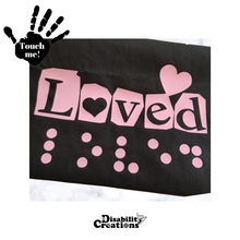 Load image into Gallery viewer, A folded black shirt with the pink design. On the top left is a black hand. On the palm, it says, &quot;Touch me.&quot; The Disability Creations logo is at the bottom.
