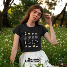 Load image into Gallery viewer, A female sitting on the glass wearing the Love in 4 Languages with hearts T-Shirt with a light yellow skirt.
