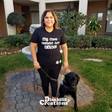 Load image into Gallery viewer, A smiley blind female wearing a "My Best Friends Has Paws" t-shirt. She is standing in front of a fountain next to her service dog.
